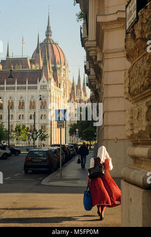 Femme portant une robe traditionnelle hongroise marche sur Budapest street contre l'édifice du Parlement Banque D'Images