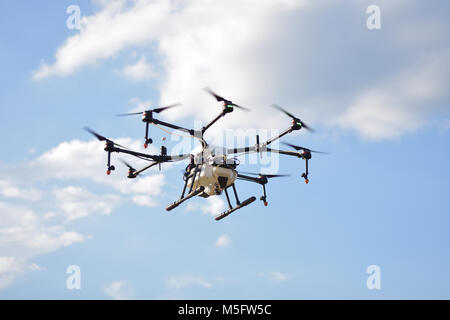 L'agriculture, de vol de drone drone photo image de l'agriculture portent un réservoir d'engrais liquide volant dans le ciel bleu se préparent à le vaporiser dans l'agriculture sont Banque D'Images