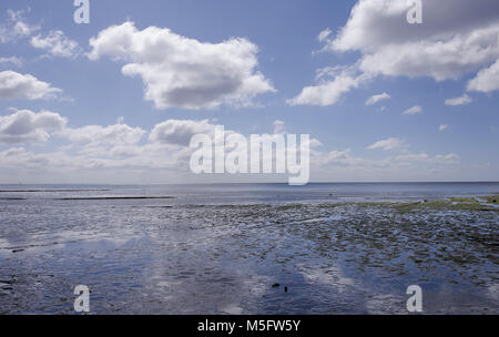 Ciel bleu et nuages blancs reflète dans l'mer calme entre Lyme Regis et Charmouth sur la côte jurassique de West Dorset, en Angleterre. Banque D'Images