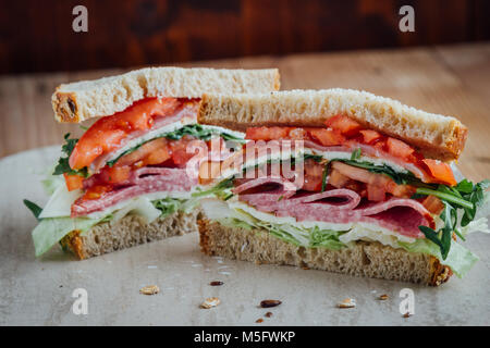 Gros sandwich à la tomate fromage jambon et salami salade ruccola Banque D'Images