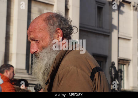 Un homme âgé, artiste de rue, à discuter avec un passant à Trafalgar Square, Londres, au cours de l'hiver soleil avec une longue barbe grise, chauve et cheveux bouclés Banque D'Images