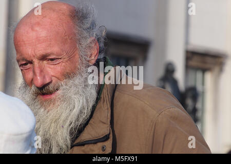 Un homme âgé, artiste de rue, à discuter avec un passant à Trafalgar Square, Londres, au cours de l'hiver soleil avec une longue barbe grise, chauve et cheveux bouclés Banque D'Images