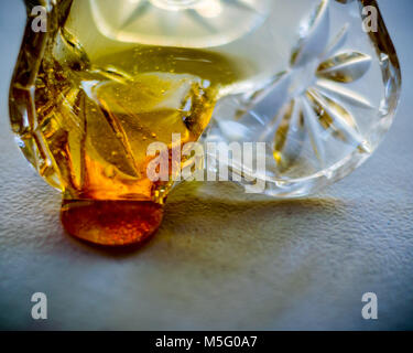 Bol en verre dégoulinant de miel, gros plan, discrète, selective focus. Le miel, le sirop d'or liquide versé d'un bocal en verre, de l'alimentation macro. Banque D'Images