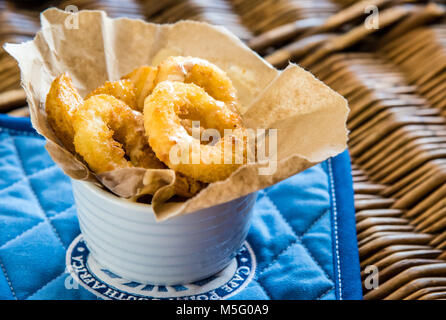 Anneaux de calmars frits et des chips, vue d'en haut photo macro, photographie alimentaire. Fish and chips en papier, vaisselle blanche, sur fond bleu, gros plan, low angle view. Banque D'Images