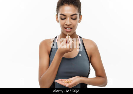 Concept de remise en forme et en bonne santé - Closeup portrait of beautiful African American prendre une pilule d'huile de foie de morue. Isolé sur fond blanc studio. Banque D'Images