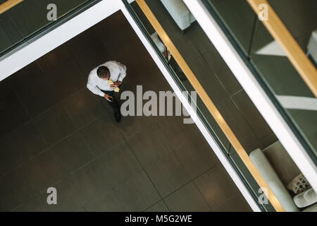 Top View of mature businessman walking via office hall. Employée de bureau dans le couloir. Banque D'Images