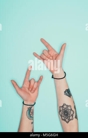 Cropped shot of woman showing cornes signe avec mains isolé sur turquoise Banque D'Images