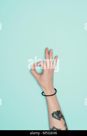 Cropped shot of woman showing okay sign isolé sur turquoise Banque D'Images