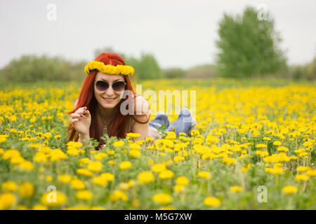 Une fille dans les verres se trouve au milieu d'un champ de fleurs Banque D'Images