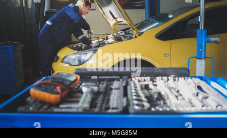 Location de l'électronique automobile - réparation de voiture - mécanicien dévisse détail de l'automobile - service de garage Banque D'Images