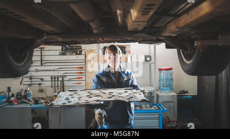 Mécanicien dans un garage automobile réparation voiture levée atelier sous Banque D'Images