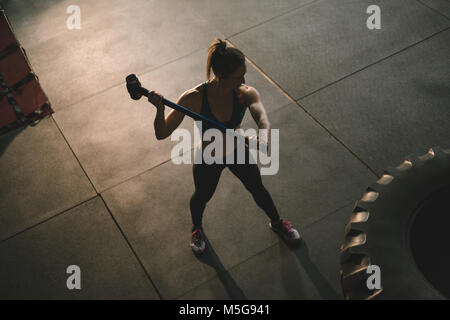 Femme musclée des pneus des roues frappant avec un marteau Banque D'Images