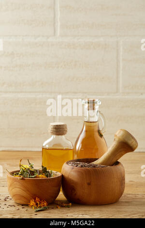 Belle la vie toujours de deux pots d'huile en verre transparent, mortier et pilon en bois coloré avec de l'herbe, y compris motley coltsfoot, tilleul et calendula Banque D'Images