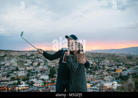 Un beau couple au coucher du soleil selfies sur fond de la ville de Göreme, en Cappadoce en Turquie. Banque D'Images