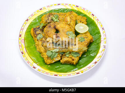 La nourriture de poisson indien Bengali savoureux de masala Rohu curry de poisson servi sur des feuilles de banane avec de la coriandre et rondelle de citron. Banque D'Images