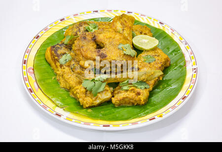 La nourriture de poisson indien Bengali savoureux de masala Rohu curry de poisson servi sur des feuilles de banane avec de la coriandre et rondelle de citron. Banque D'Images