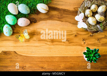 Joyeuses Pâques en plongée des comme flatlay avec rétro coloré des œufs de Pâques, de l'herbe, un papillon, nid de Pâques sur table en bois Banque D'Images