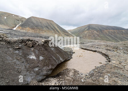 La fin du glacier. Une rivière marron, la fonte de la Glacier Longyear, venant de sous la glace. Longyear Valley. Moraine glaciaire arctique paysage de pierres et montagnes, Svalbard. Banque D'Images