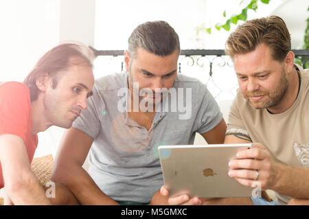 Didim, Turquie - 01 octobre 2017 : Trois hommes occasionnels avec un iPad de discuter sur un projet d'affaires dans le balcon sur une journée ensoleillée. Banque D'Images