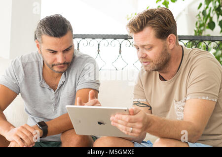 Didim, Turquie - 01 octobre 2017 : deux hommes occasionnels avec un iPad de discuter sur un projet d'affaires dans le balcon sur une journée ensoleillée. Banque D'Images