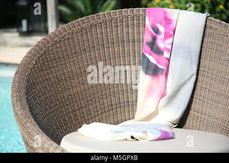 Panneaux wicker chair par piscine avec pink floral jupe drapé sur elle Banque D'Images