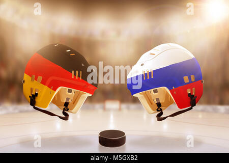 Low angle view of casques de hockey peint avec l'Allemagne et la Russie drapeaux, et rondelle de hockey sur glace en pleine lumière arrière-plan du stade. Banque D'Images