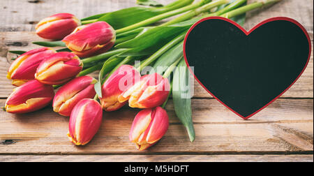 Le jour de la Saint-Valentin. Tulipes et une forme de coeur blanc sur fond de bois, de l'espace pour le texte Banque D'Images
