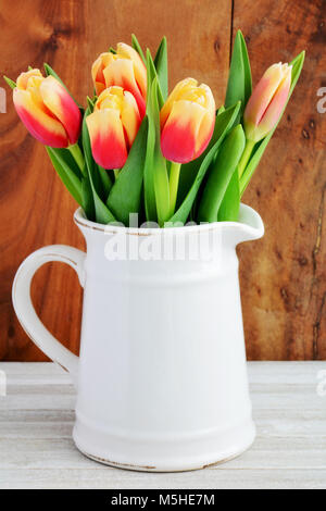 Tulipes rouges et jaunes dans la verseuse vintage en format vertical et tourné en lumière naturelle Banque D'Images