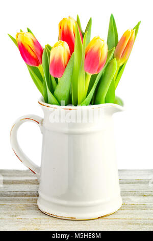 Tulipes rouges et jaunes en céramique ancienne verseuse en format vertical. Tourné en lumière naturelle. Banque D'Images