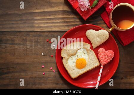 Petit-déjeuner de Saint Valentin en forme de coeur pain frit oeufs toast café servi en plaque rouge, vue du dessus Banque D'Images