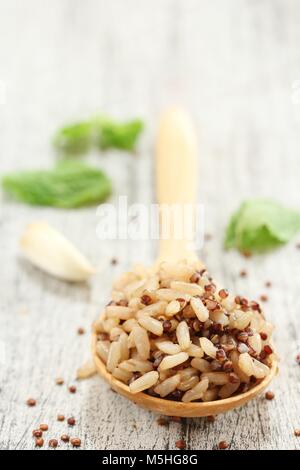 Le quinoa cuit le riz brun dans une cuillère en bois sur fond blanc rustique, selective focus Banque D'Images