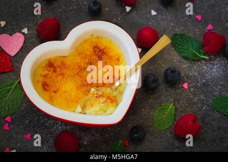 Crème brûlée de fissuration de la croûte de sucre avec une cuillère à dessert, Close up, selective focus Banque D'Images