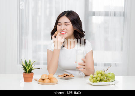 Pretty young asian woman eating cookie délicieux à la maison. Banque D'Images