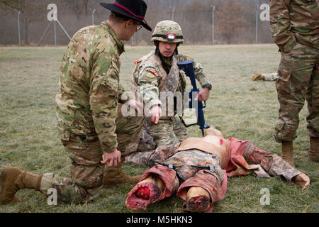 Un soldat géorgien du 11e Bataillon d'infanterie légère, 1re Brigade d'infanterie géorgiennes, les Forces terrestres, explique comment il est le traitement d'une victime simulée au SPC. Wesley Hobson, un infirmier affecté à l'Escadron, 2d 4ème régiment de cavalerie, épargnant la vie au cours d'un combat le 9 février 2018 bien sûr, au centre de formation de simulation médicale dans la zone d'entraînement Grafenwoehr, Allemagne. Les soldats s'entraînent avec U.S. Marine Corpsmen pour un prochain déploiement en Afghanistan. Les soldats ont chargé le cours sont à partir de la 2e et 7e régiment de cavalerie de la commande d'entraînement de l'armée. ( Banque D'Images