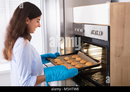 Portrait Of A Smiling Woman Taking Bac de petits gâteaux du four Banque D'Images