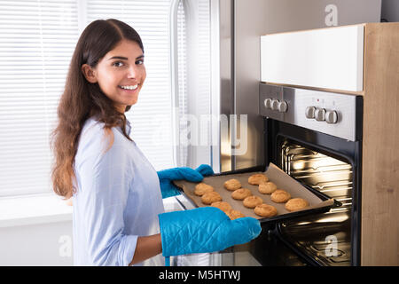 Portrait Of A Smiling Woman Taking Bac de petits gâteaux du four Banque D'Images