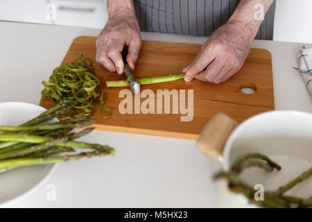 Man peeling les asperges sur une planche à découper rustique Banque D'Images