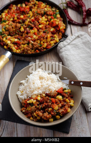 Chili con carne et piment rouge avec du riz sur une table rustique Banque D'Images