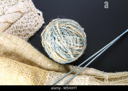 Une balle de laine avec des aiguilles à tricoter et de chaussettes sur un tableau gris. La couture Banque D'Images