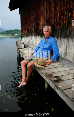 Portrait of smiling senior man sitting on jetty en été Banque D'Images