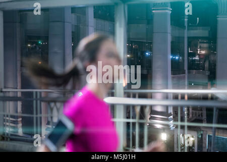 Jeune femme en rose sportshirt fonctionnant en ville la nuit Banque D'Images