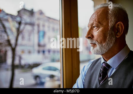 Elegant man looking out of window Banque D'Images