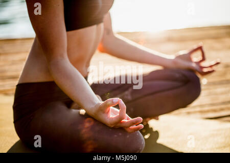 Close-up of woman practicing yoga on jetty at un lac Banque D'Images