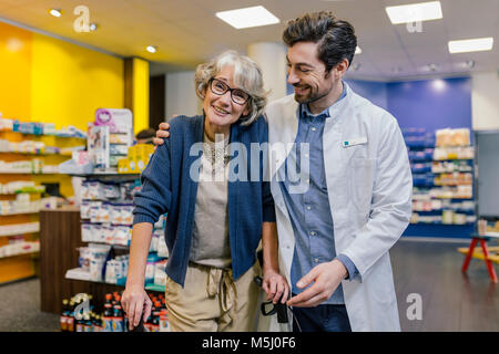 Portrait of smiling pharmacien et client avec roues walker en pharmacie Banque D'Images