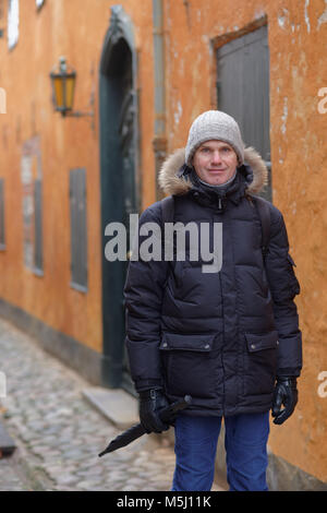 Homme mature dans les vêtements d'hiver dans une rue étroite d'Elseneur, Danemark Banque D'Images