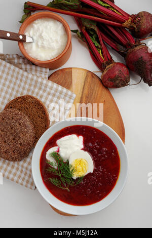 Polonaise traditionnelle soupe de betteraves avec oeuf mollet et de crème sure sur une table rustique avec les betteraves fraîches Banque D'Images
