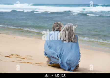 Couple sur la plage, enveloppé dans une couverture Banque D'Images