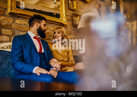 Elegant couple sitting on couch talking Banque D'Images