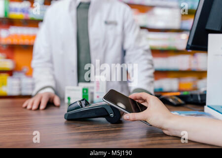 Close-up of woman with smartphone sans espèces dans une pharmacie Banque D'Images