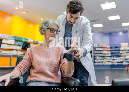 Pharmacien de prendre la tension artérielle de client en pharmacie Banque D'Images